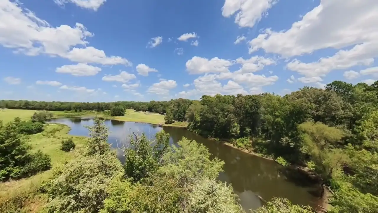 The larger pond seen from a wooded rise under a sky full of cumulus clouds